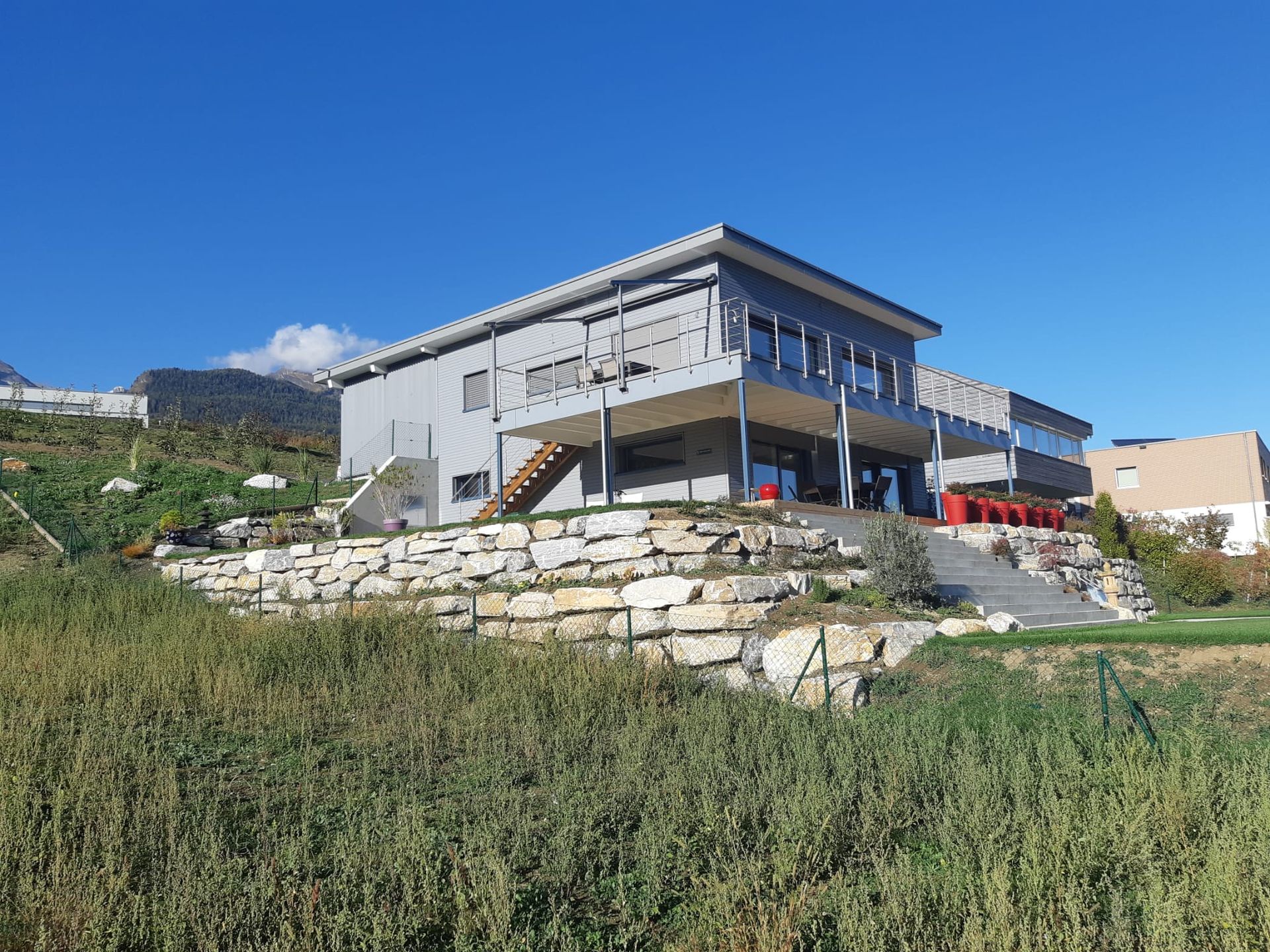Une grande maison est située au sommet d'une colline herbeuse.