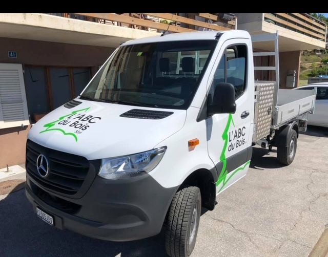 Une camionnette Mercedes blanche est garée devant un bâtiment