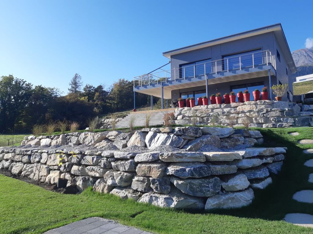 Une grande maison avec un grand mur de pierre devant elle.