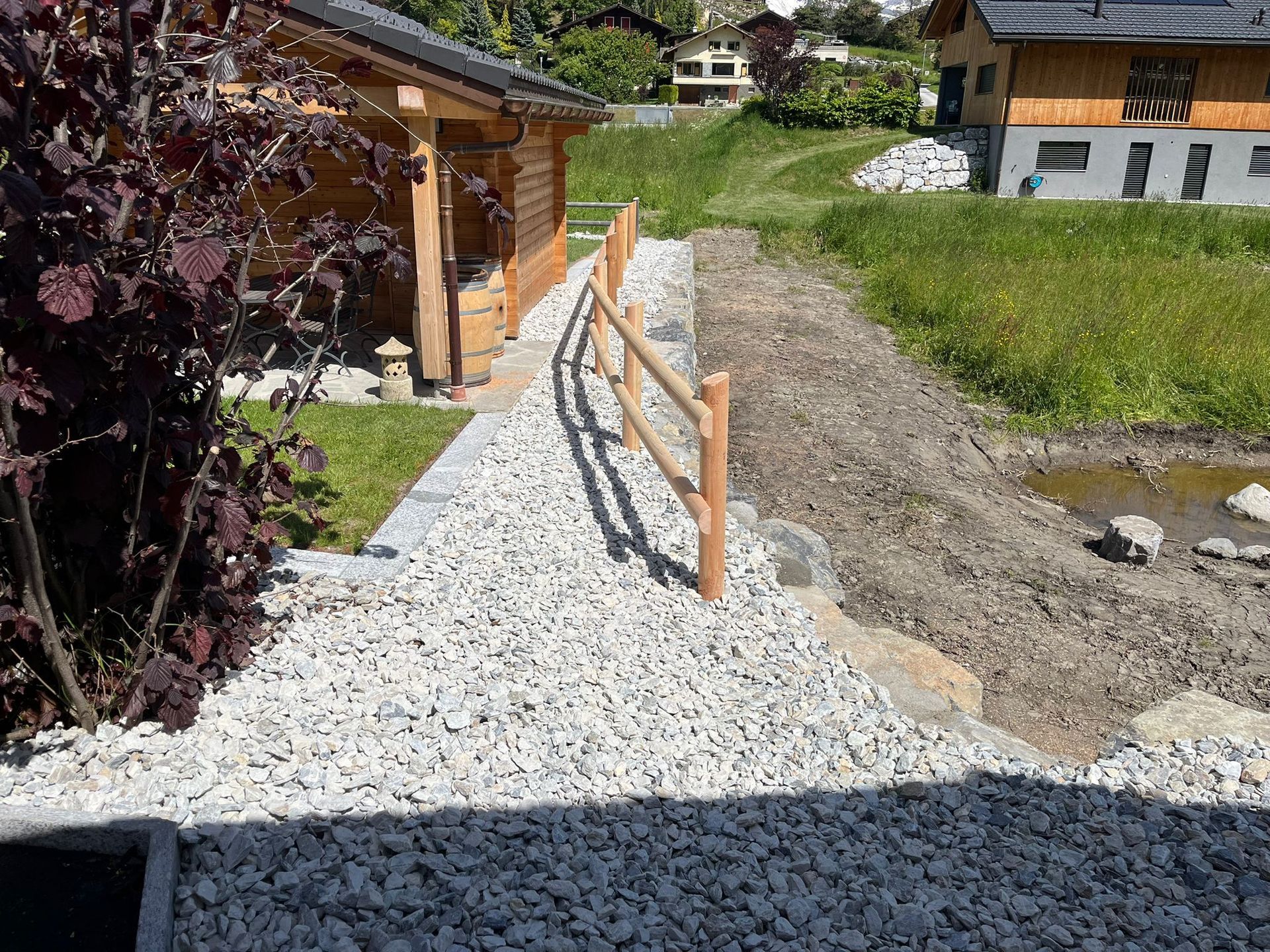Une clôture en bois entoure un chemin de gravier menant à une maison.