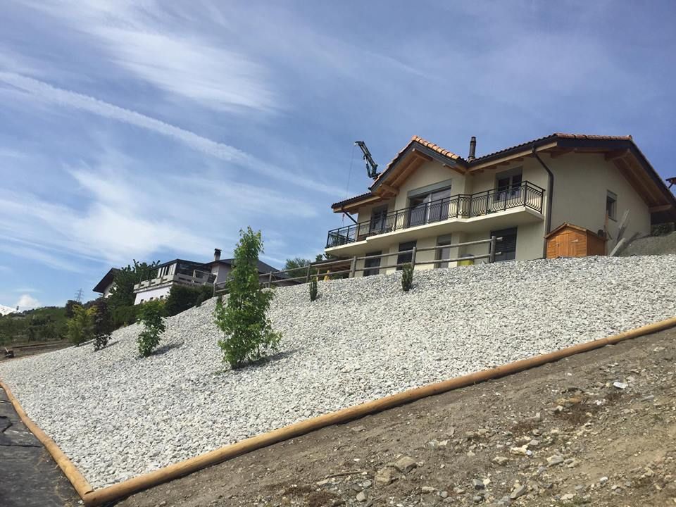 Une grande maison est située au sommet d'une colline entourée de gravier.