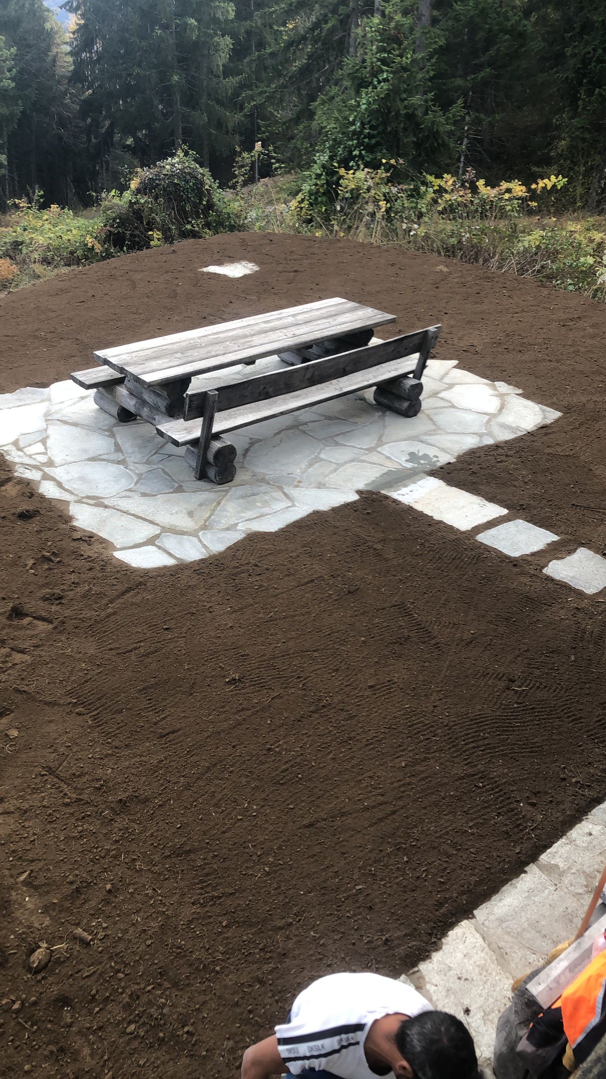 Une table de pique-nique est posée au milieu d'un champ de terre.