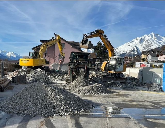 Deux excavatrices travaillent sur un chantier de construction avec des montagnes en arrière-plan