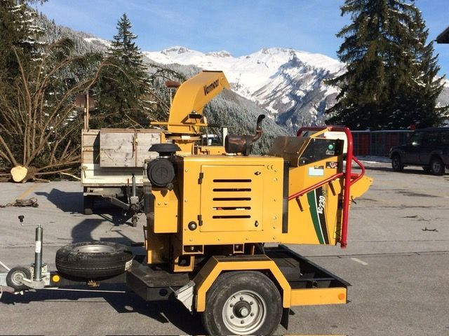 Une machine jaune est garée sur un parking avec des montagnes en arrière-plan