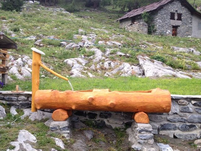 Une fontaine en bois avec un mur de pierre en arrière-plan