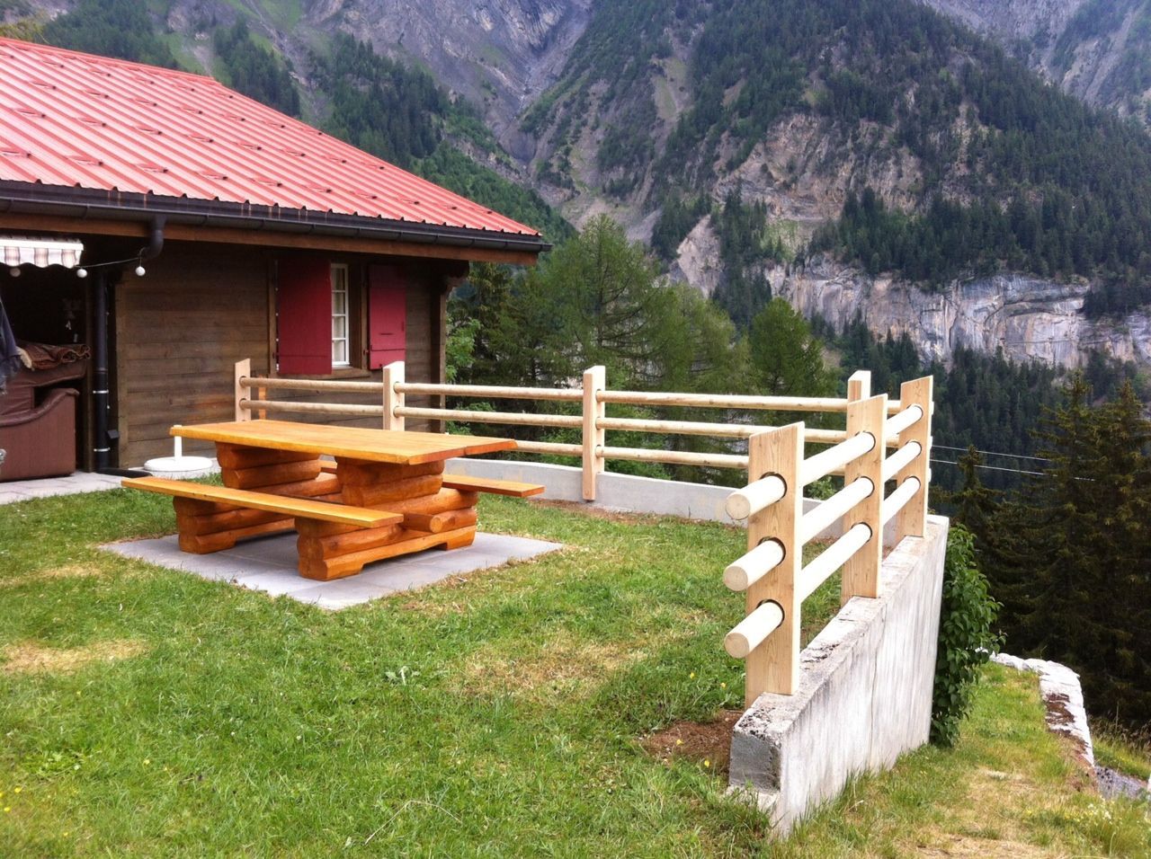 Une table de pique-nique en bois devant une maison avec des montagnes en arrière-plan