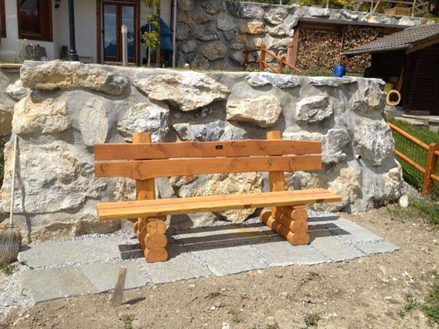 Un banc en bois est assis devant un mur de pierre
