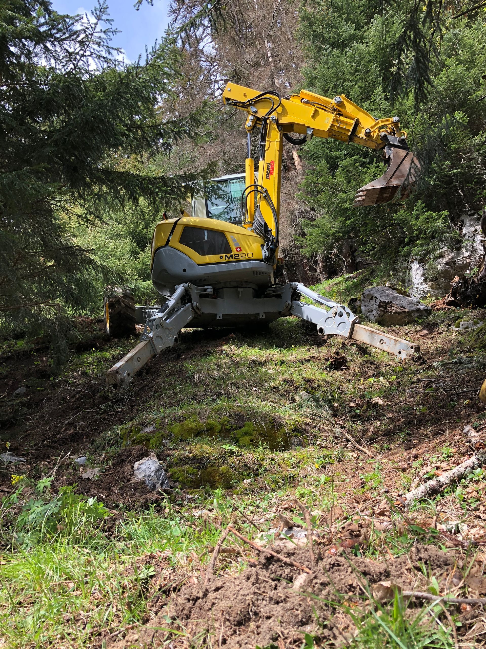 Une excavatrice jaune creuse dans la terre dans les bois.