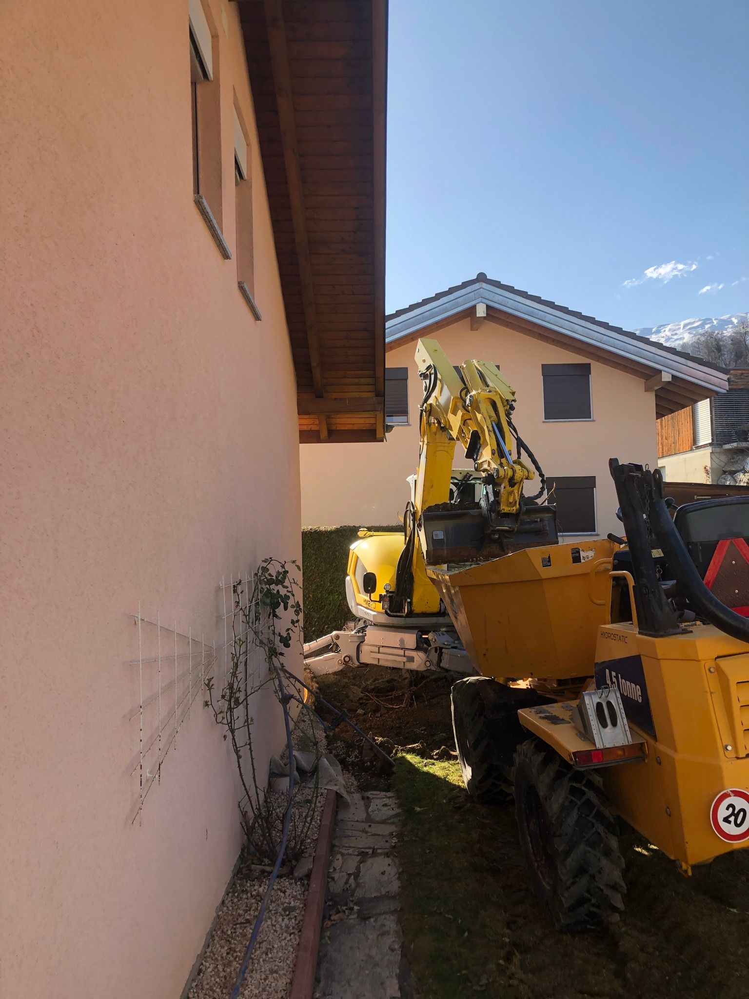 Un camion-benne jaune est garé devant une maison.