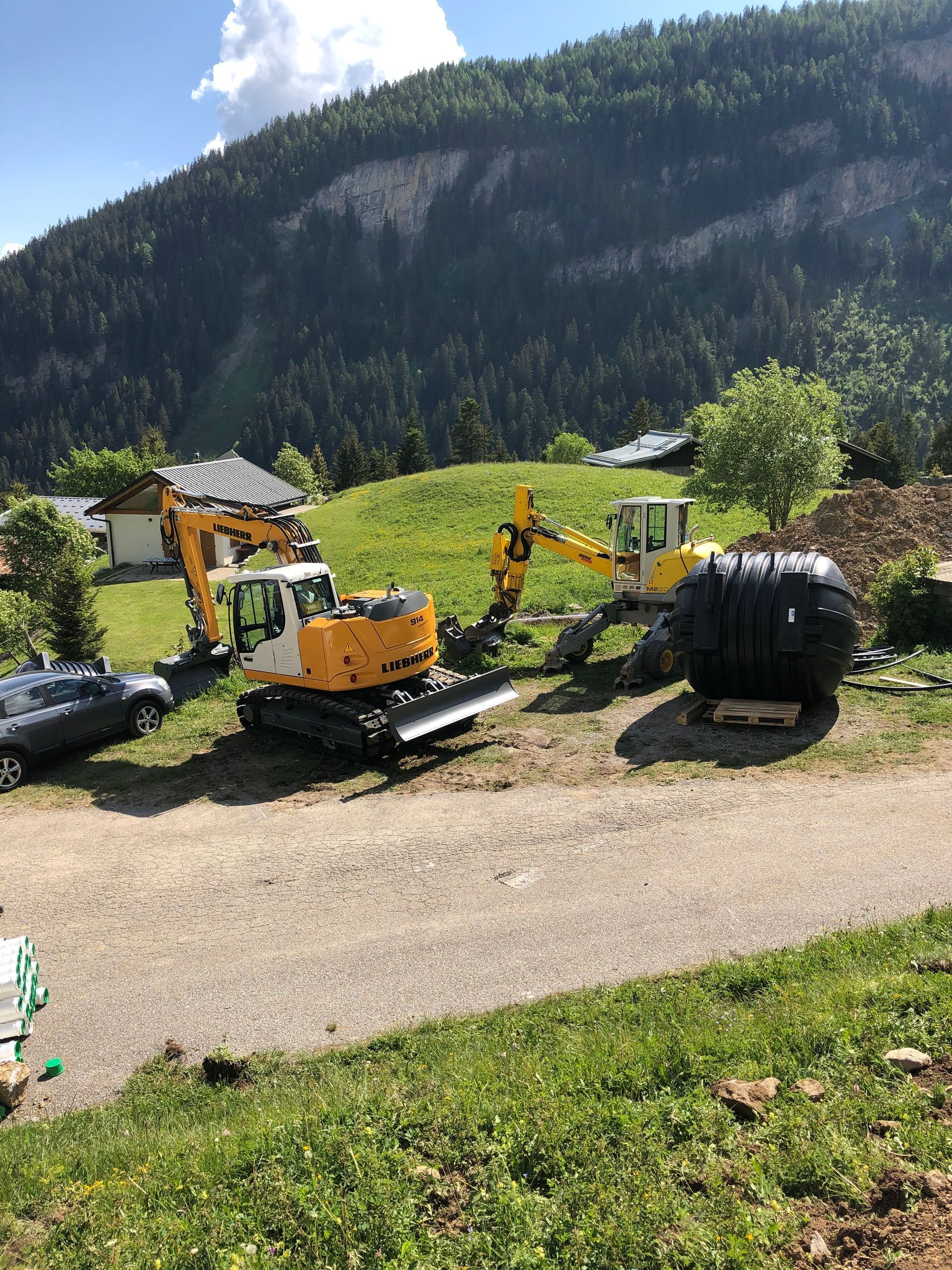 Un groupe de véhicules de construction est garé sur le bord d'un chemin de terre.