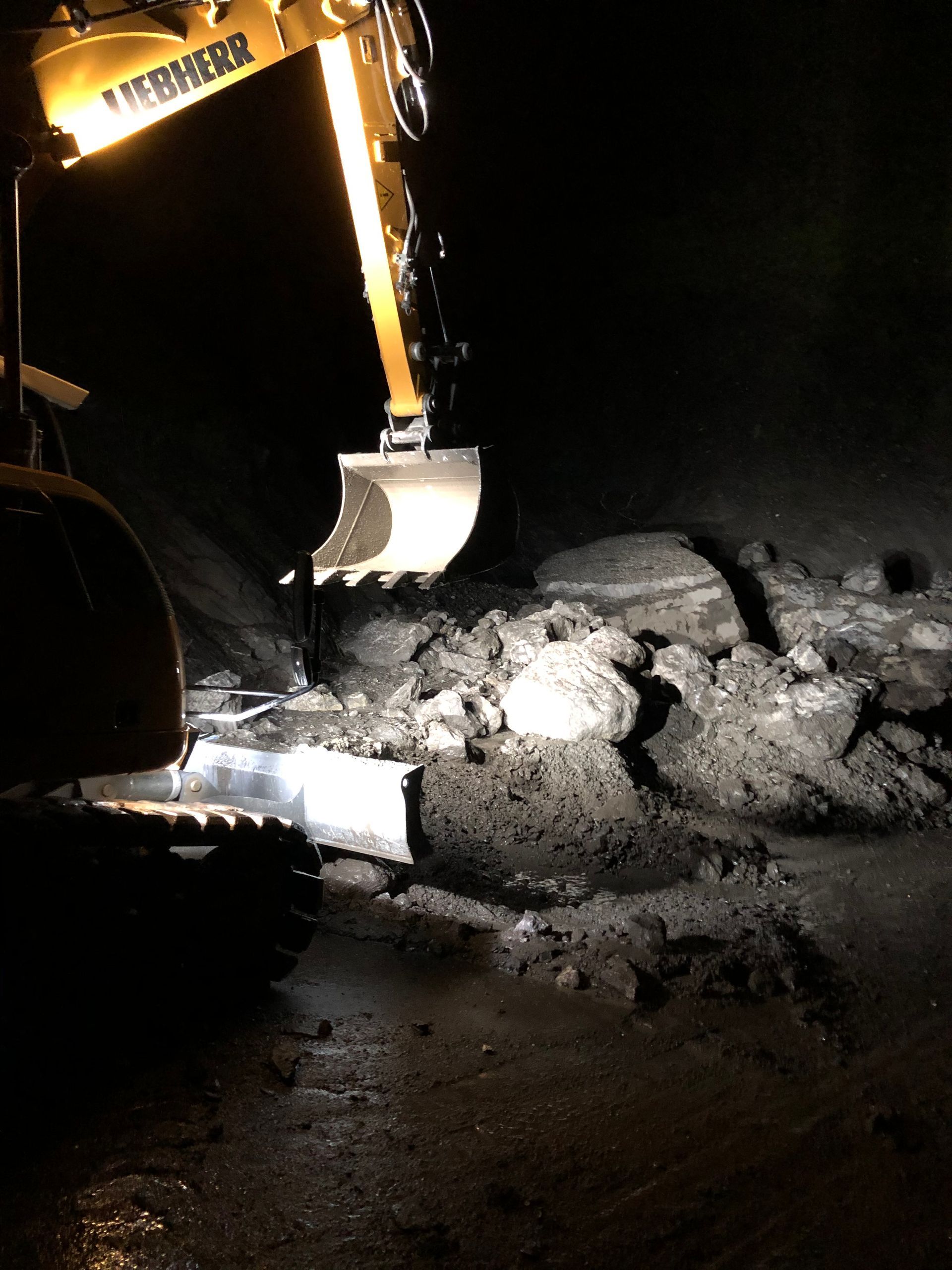 Un bulldozer creuse un trou dans le sol la nuit.