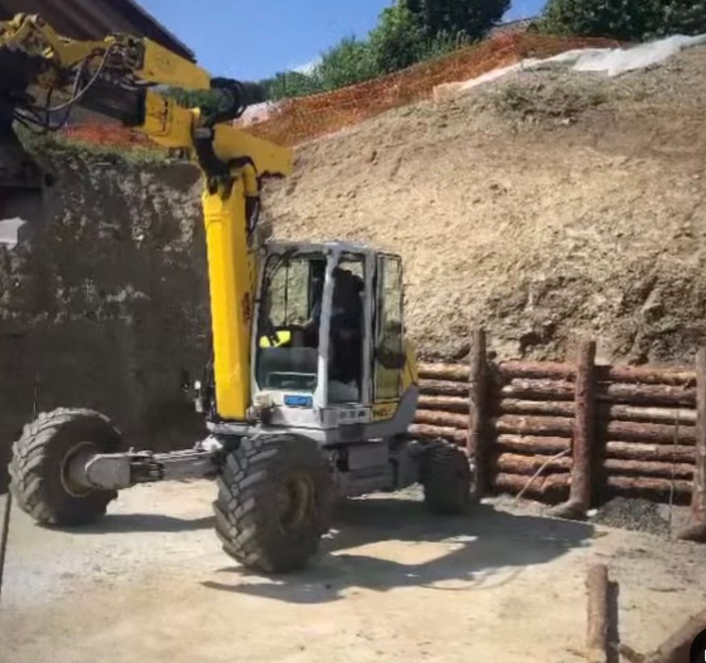 Un chariot élévateur jaune est garé devant un tas de bûches.
