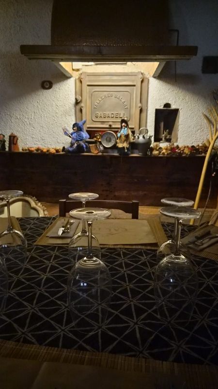 Acogedor comedor con mesa y sillas de madera, alfombra estampada y chimenea decorativa con una cálida iluminación