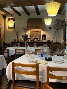 Acogedor comedor de restaurante, con mesas preparadas, manteles blancos, lámparas colgantes y vigas rústicas en el techo