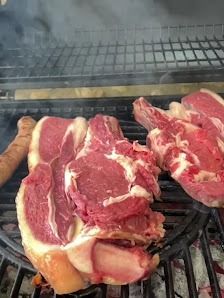 Filetes crudos chisporroteando en una parrilla mientras sube el humo, uno a la izquierda y dos a la derecha.