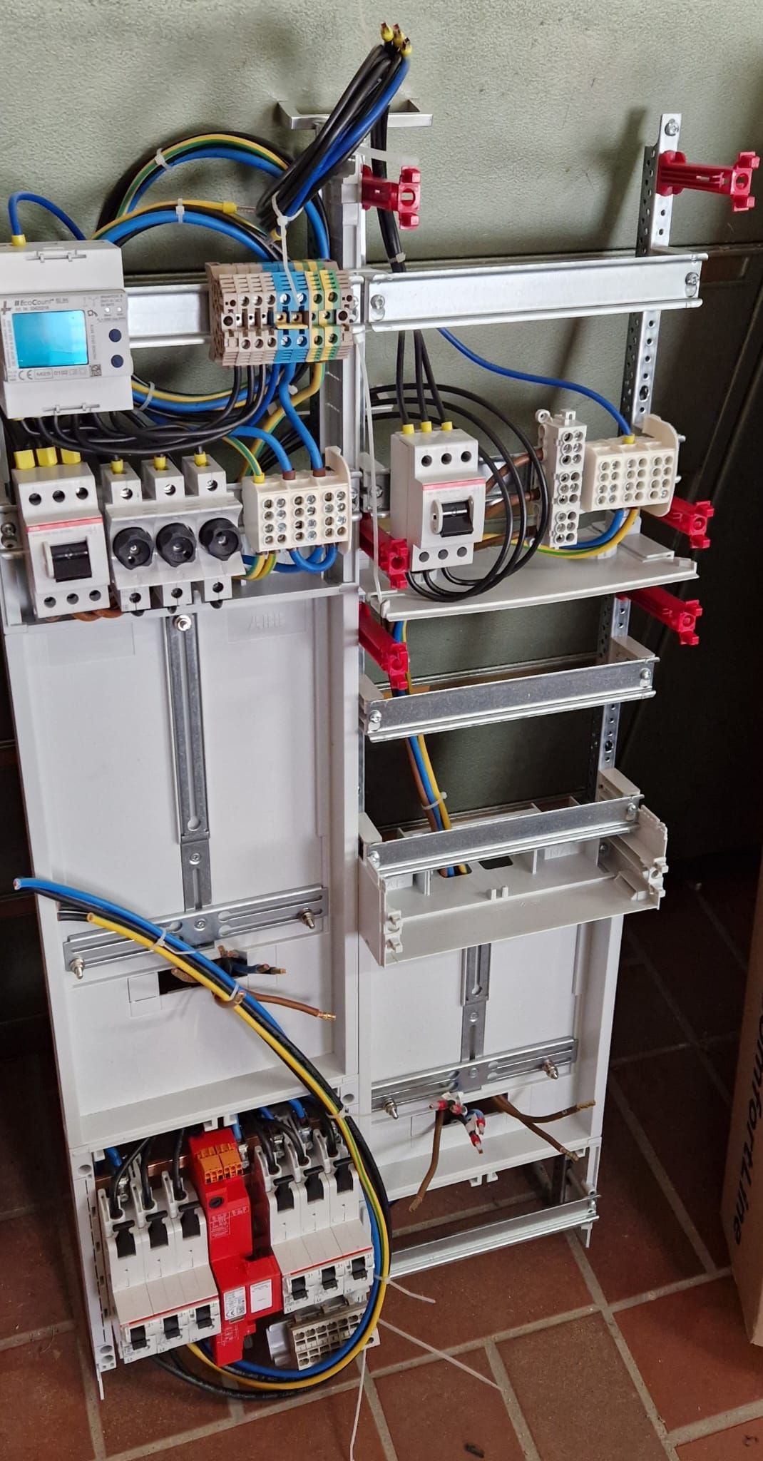 Elektrisches Bedienfeld mit Verkabelung, Leistungsschaltern und auf Schienen montierten Komponenten.