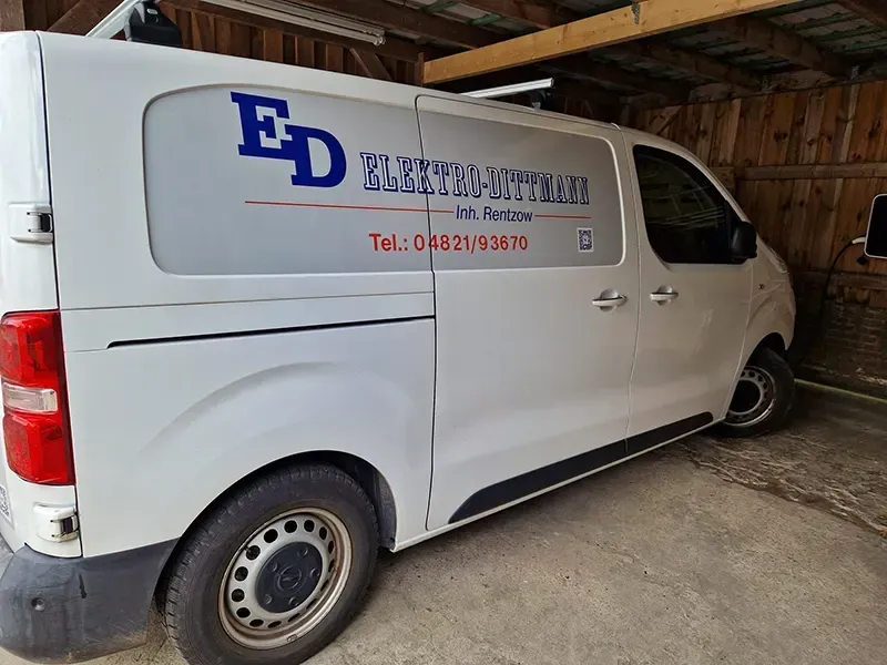 Weißer Lieferwagen mit „ED Elektro-Dienst“-Logo und Telefonnummer in einem Schuppen geparkt.