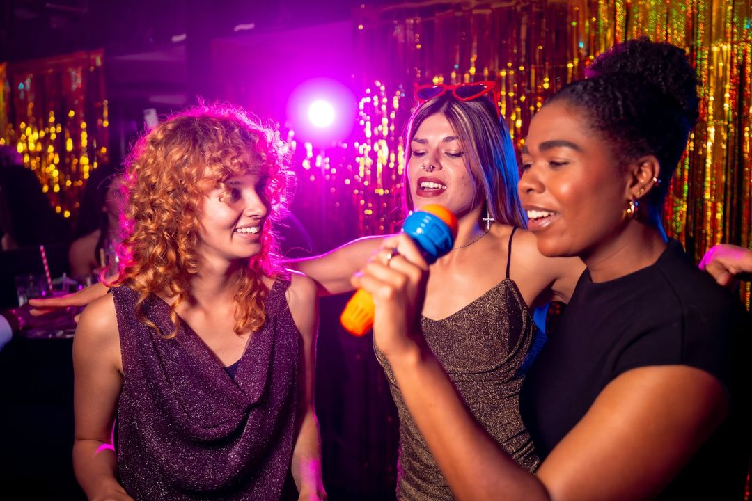 Un grupo de mujeres canta con micrófonos en una fiesta de karaoke.