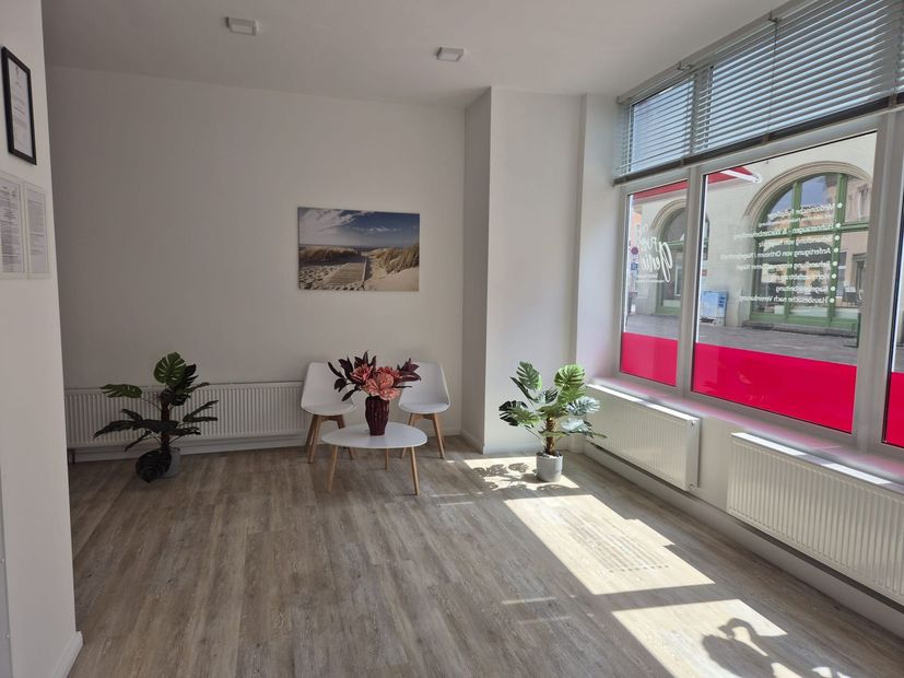 Ein Wartezimmer mit einem Tisch und Stühlen und einem Gemälde an der Wand.