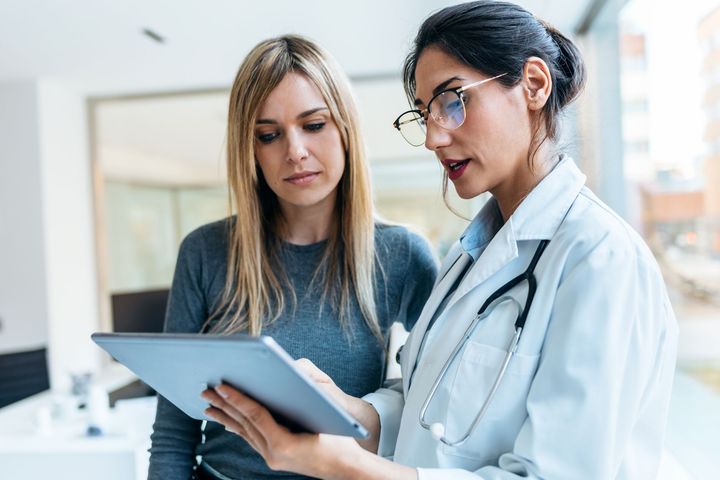 Um médico e um paciente estão a olhar para um tablet juntos.