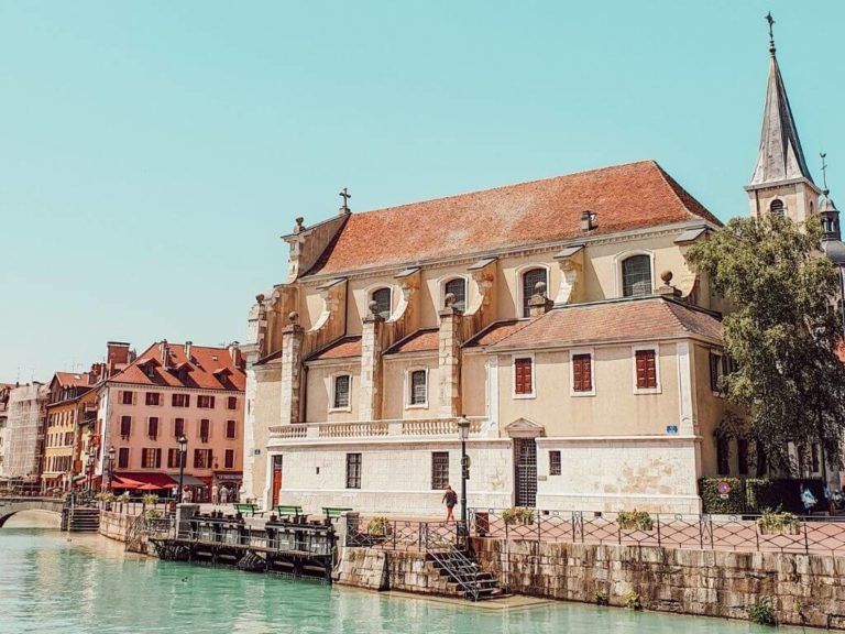 Des maisons de ville en bord de mer et une église au bord d'un canal sous un ciel bleu clair