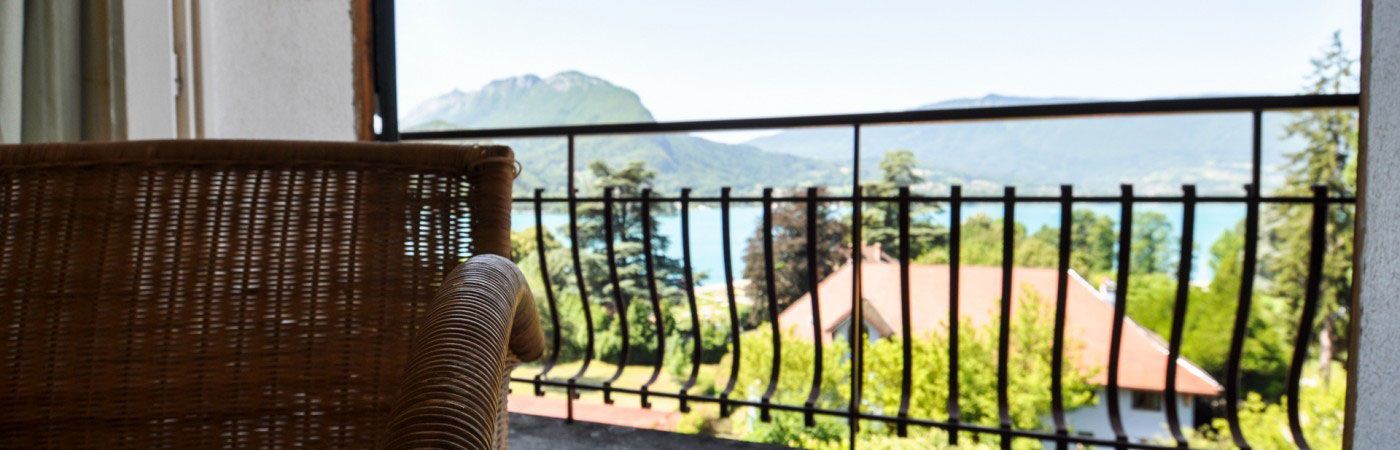 Vue depuis un balcon sur une plage tropicale, encadrée par une balustrade noire et une chaise en osier.