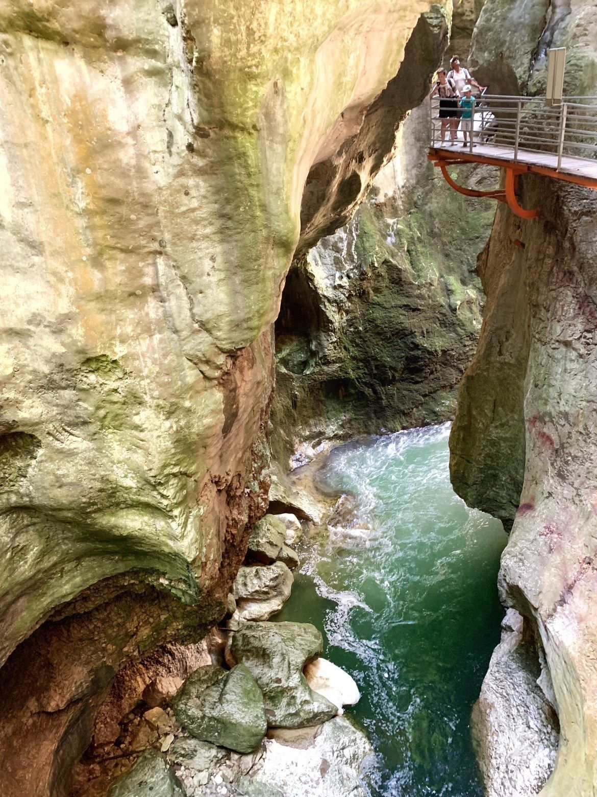 Gorge rocheuse étroite aux eaux turquoise et pont de passerelle rouge en hauteur