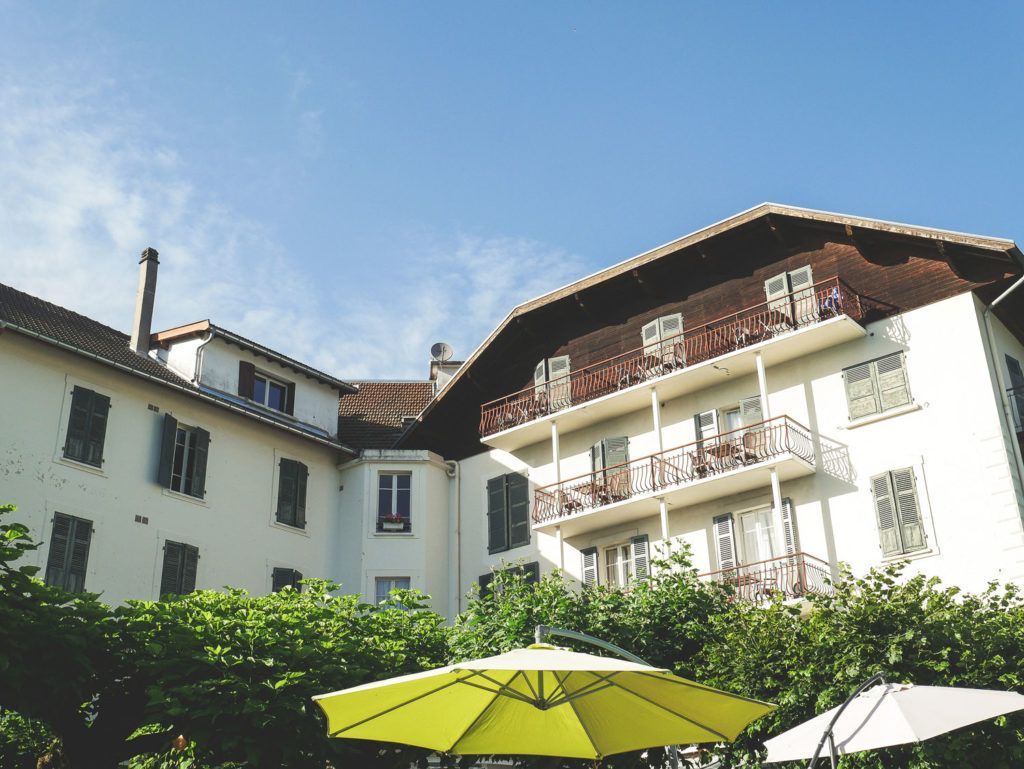 Cour intérieure d'un immeuble blanc avec balcons et parasols verts sous un ciel bleu