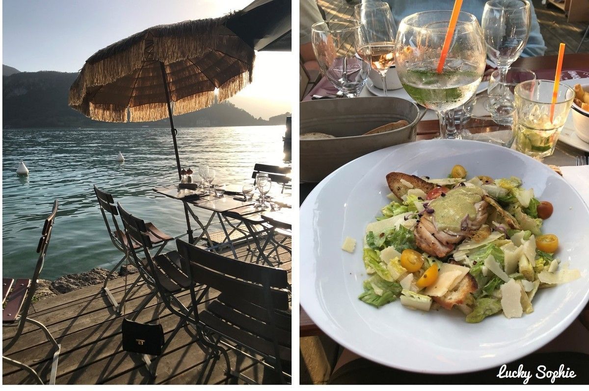 Dîner en bord de mer au coucher du soleil, avec parasol, chaises longues, boisson et salade dressée sur une table.