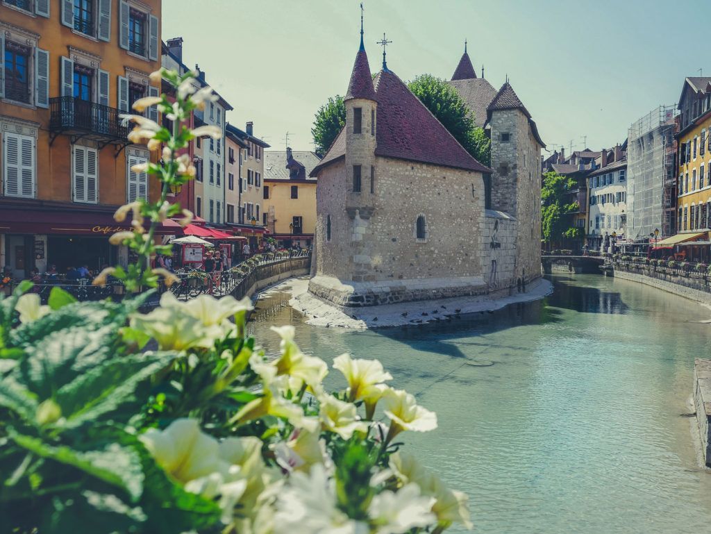 Canal dans une ville européenne avec des bâtiments en pierre et des fleurs au premier plan