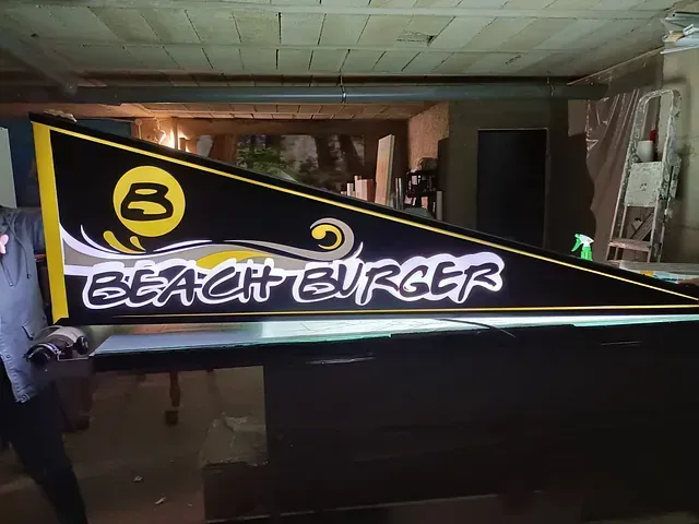 Un cartel de hamburguesa de playa está iluminado en una habitación oscura.