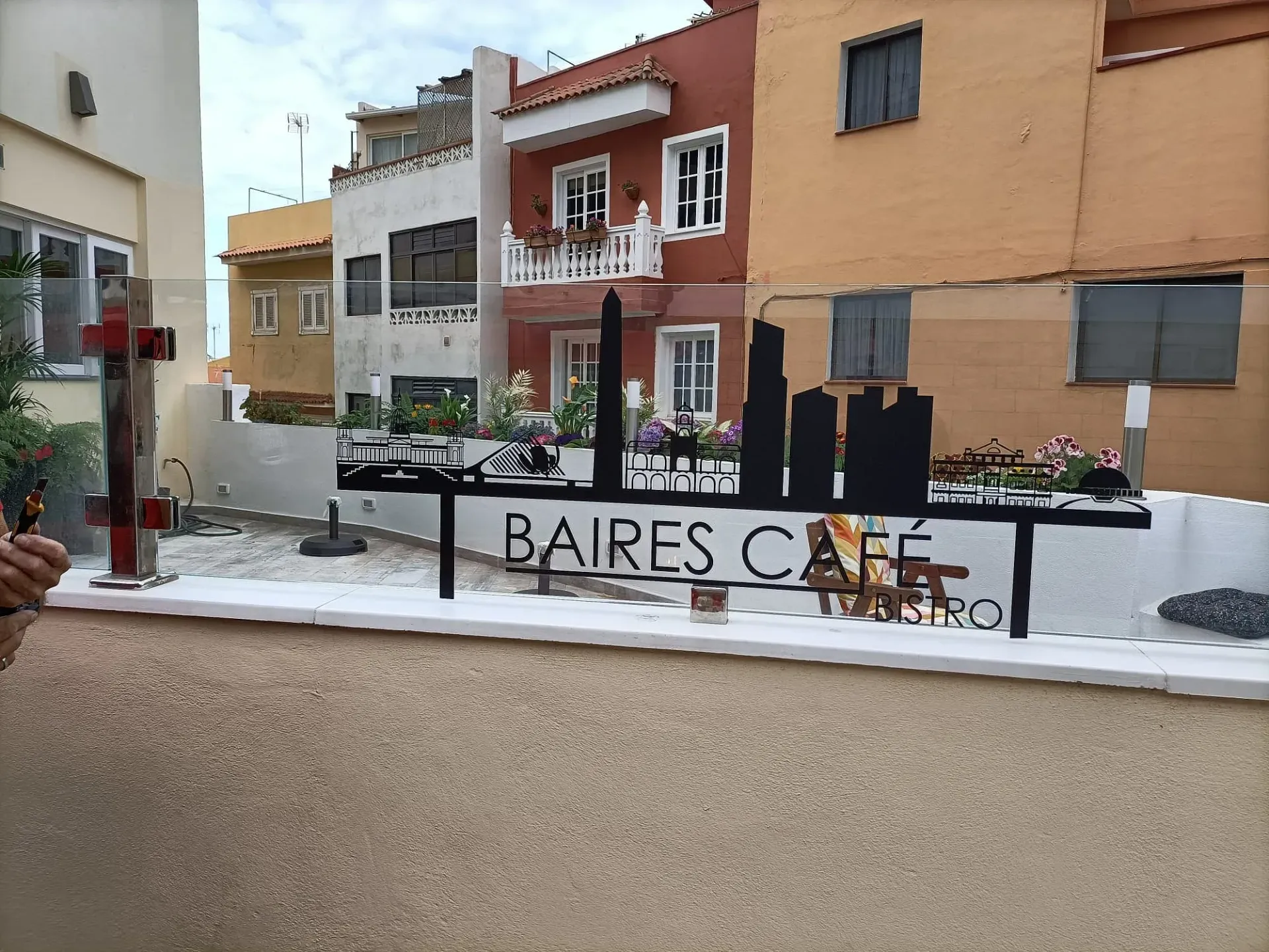 Una persona está tomando una foto de un cartel que dice Baires Cafe.