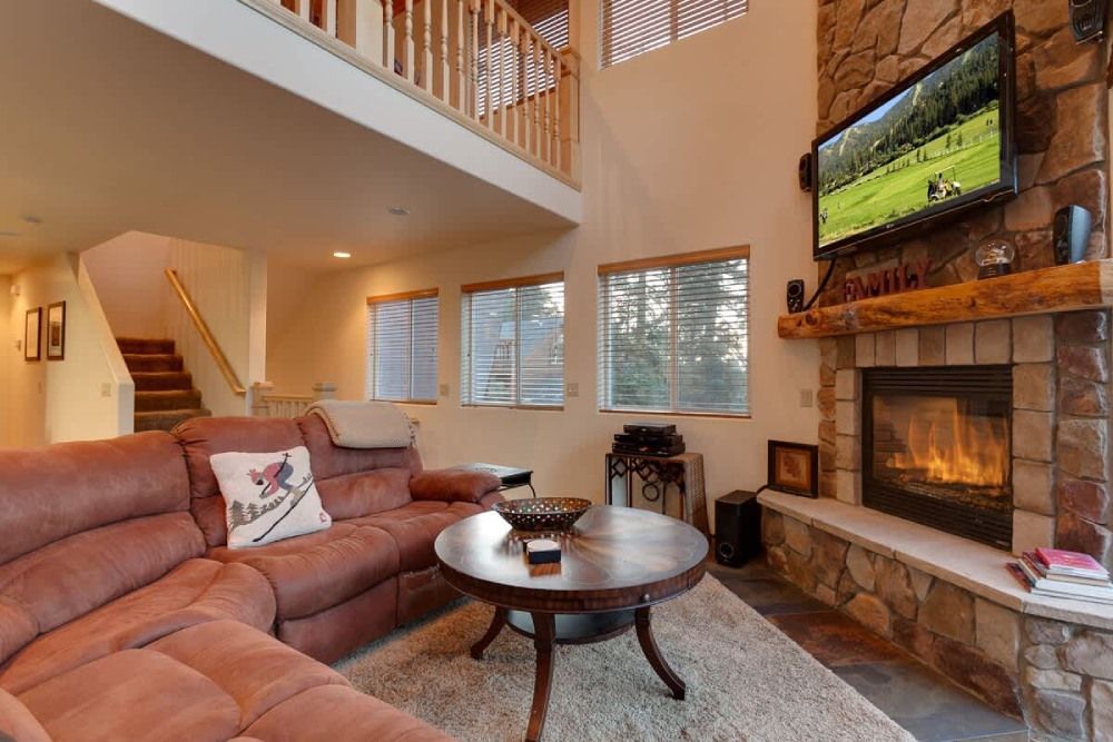 Cozy living room with sectional sofa, fireplace, TV, staircase, and lofted ceiling