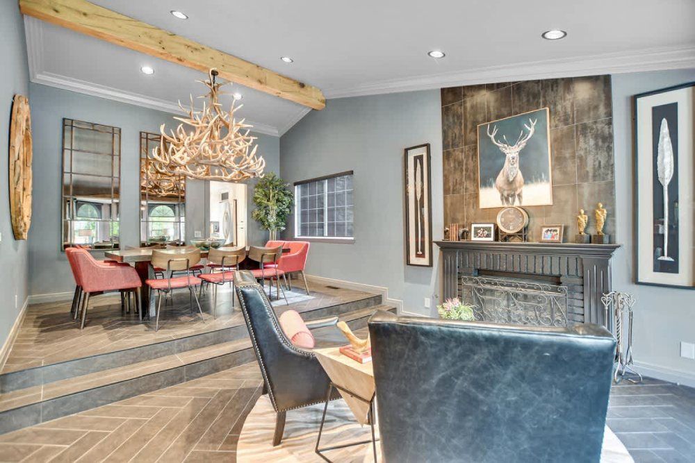 Elegant dining room with a chandelier, red chairs, and a large deer painting above the fireplace.