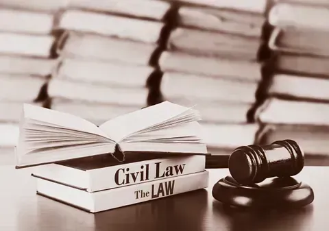 Una pila de libros de derecho civil y un mazo de juez sobre una mesa.