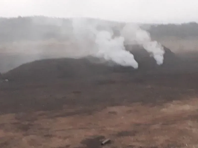 Sale humo de un montón de tierra en un campo.
