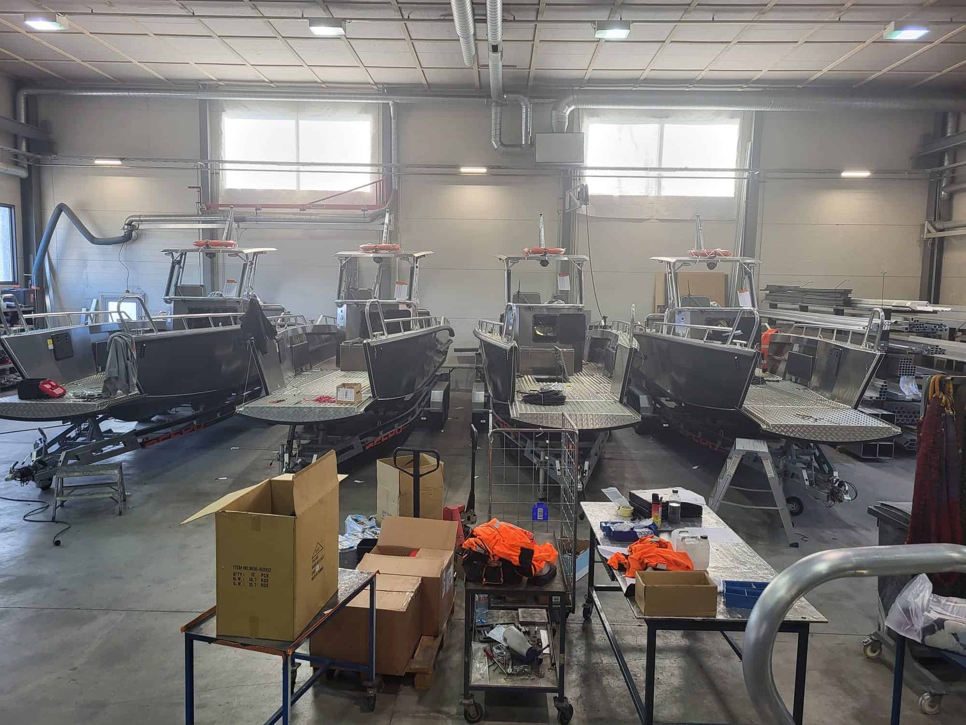Four boats under construction inside a large workshop with tools and materials.