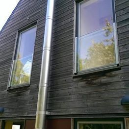 Ein Holzhaus mit zwei Fenstern und einem Schornstein an der Seite.