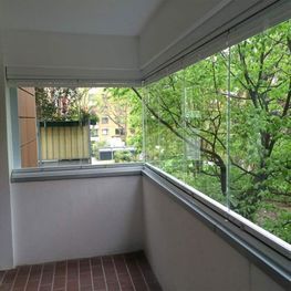 Ein Balkon mit vielen Fenstern und Bäumen im Hintergrund.