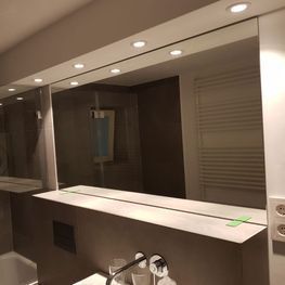 Ein Badezimmer mit großem Spiegel und Waschbecken.