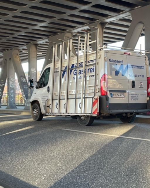 Ein weißer Lieferwagen mit dem Wort Glaserei auf der Rückseite steht unter einer Brücke