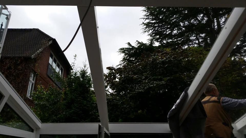 Ein Mann steht unter einem Dach, im Hintergrund sind Bäume zu sehen.