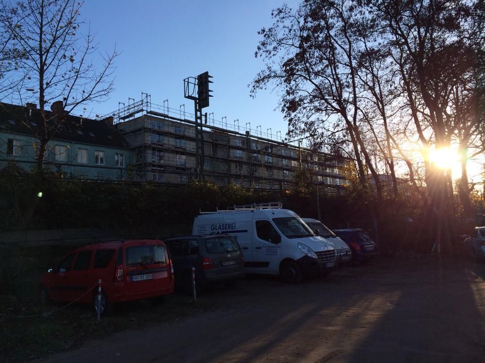 Vor einem Gebäude mit Gerüst parkt eine Reihe von Autos.