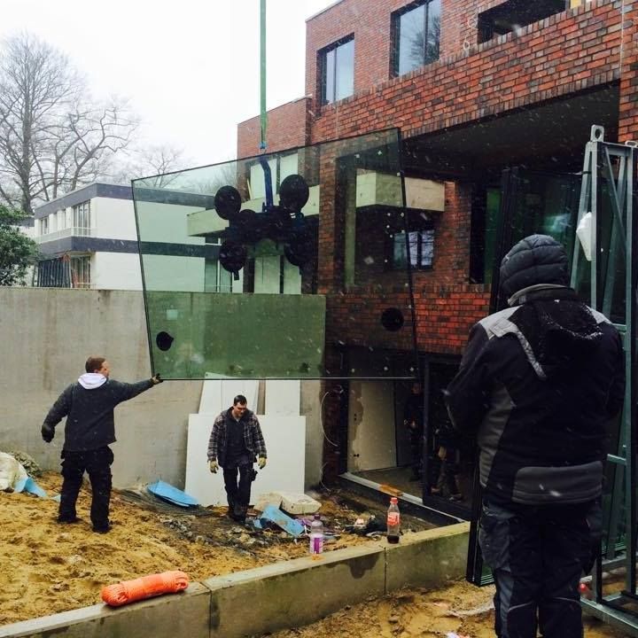 Ein Mann hält ein großes Stück Glas vor einem Backsteingebäude
