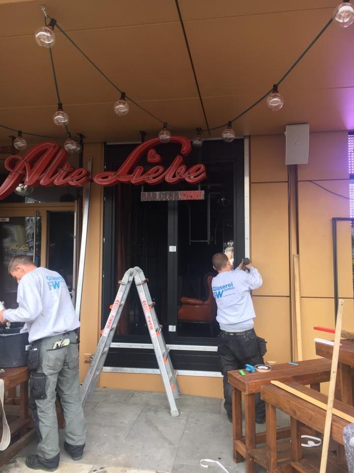 Zwei Männer arbeiten vor einem Gebäude mit der Aufschrift „alles liebe“