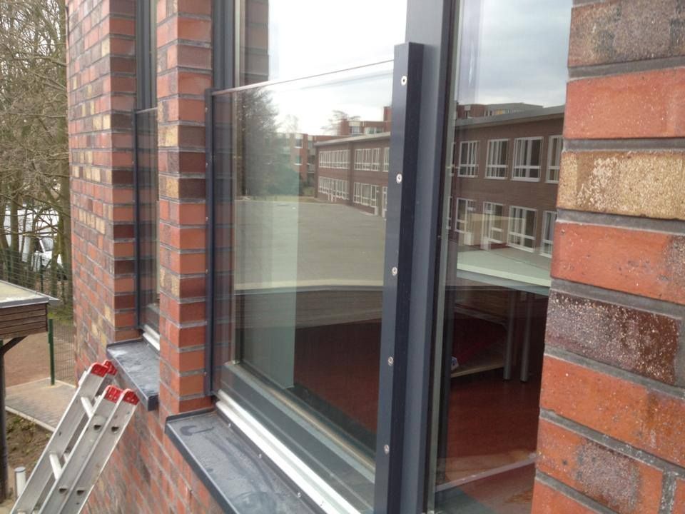 An der Seite eines Backsteingebäudes neben einem Fenster steht eine Leiter.