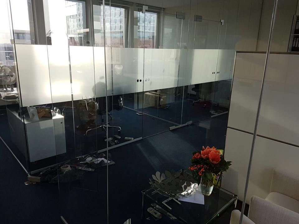 Ein Raum mit vielen Fenstern und einer Vase mit Blumen auf einem Tisch.