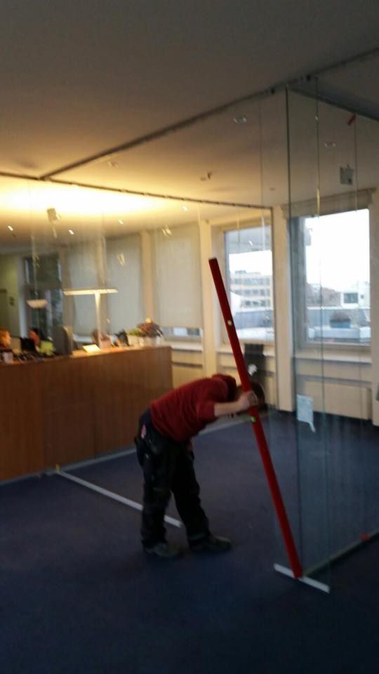 Ein Mann in einem roten Hemd hält eine rote Stange in einem Raum