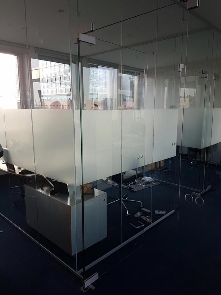 Ein Raum mit vielen Glaswänden und einem Schreibtisch.