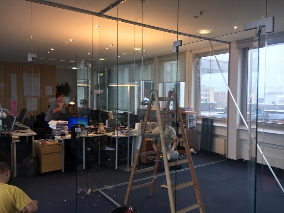 Ein Mann sitzt an einem Schreibtisch in einem Büro. Im Vordergrund ist eine Leiter zu sehen.